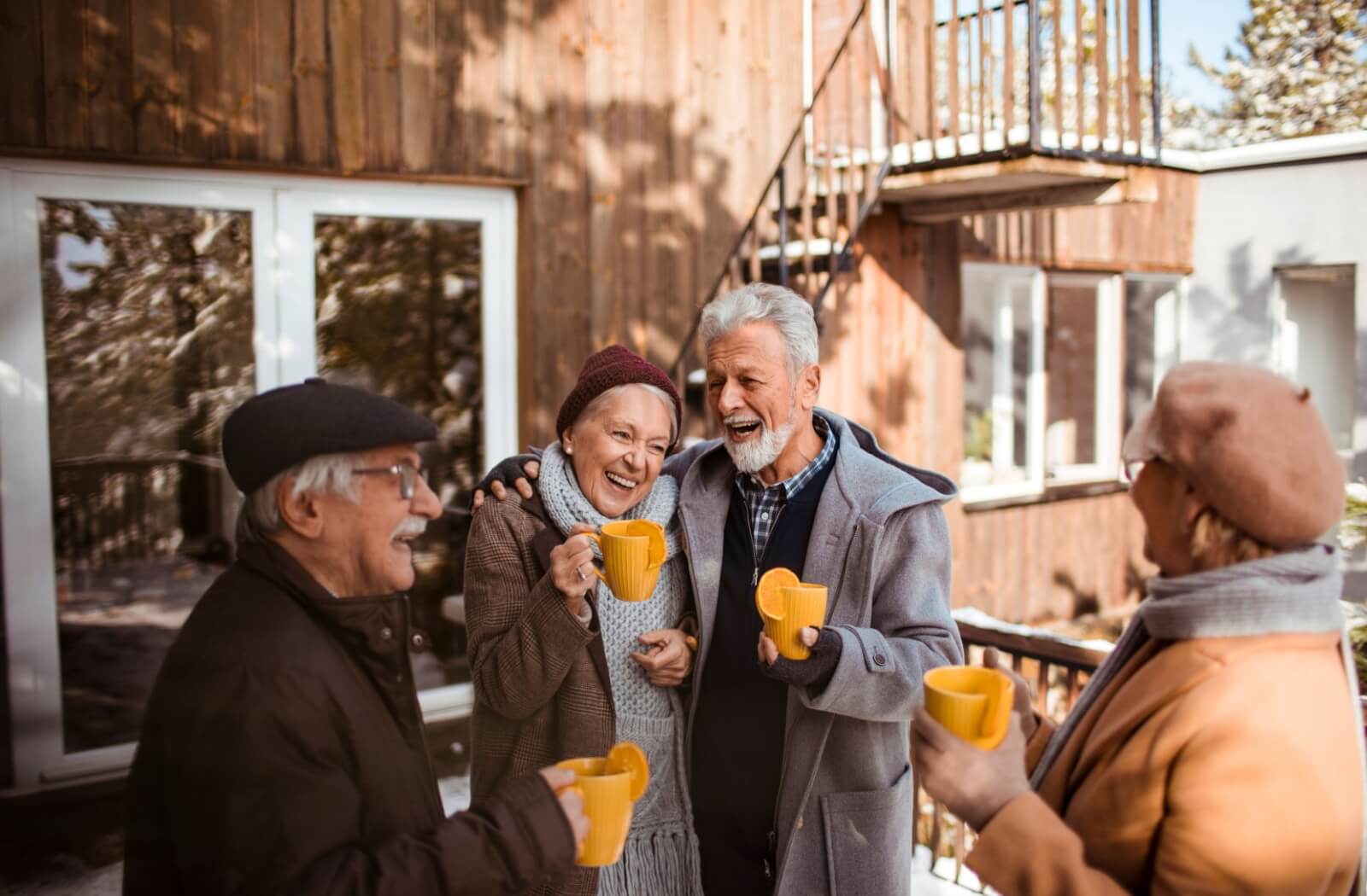 A group of seniors in assisted living share drinks together while enjoying the brisk early winter air
