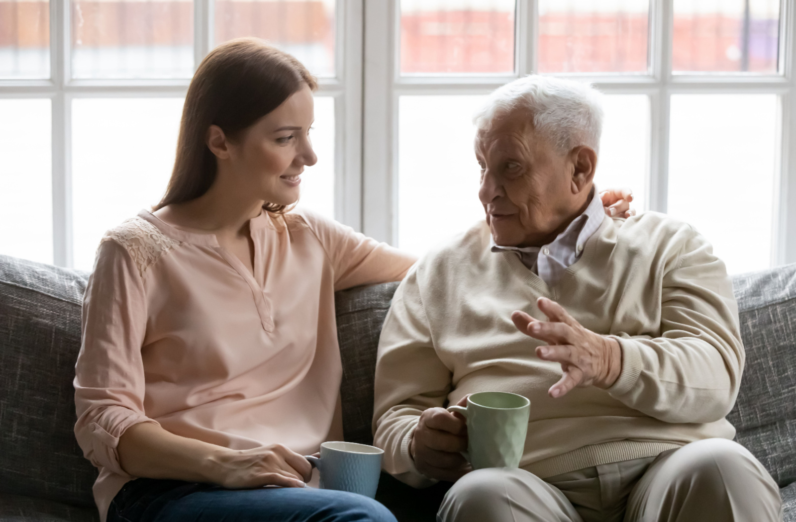 An adult child visits their older parent for a conversation over tea in memory care
